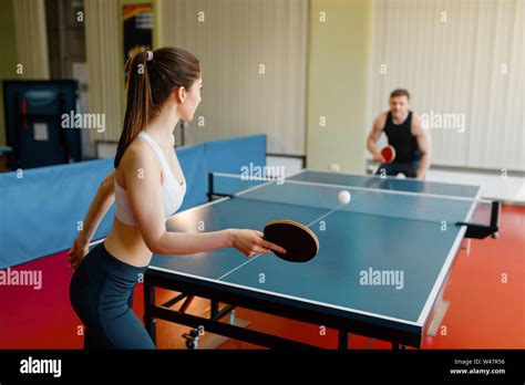 Man And Woman Playing Ping Pong Indoors Couple In Sportswear Holds Rackets And Plays Table