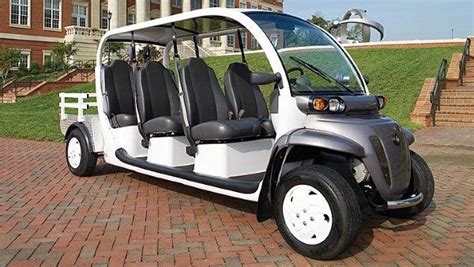 A Golf Cart With Four Seats Parked In Front Of A Large Building On A