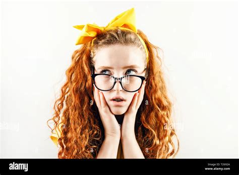 Schocked Curly Redhead Girl In Glasses With A Yellow Bow On Her Head Wearing Yellow T Shirt
