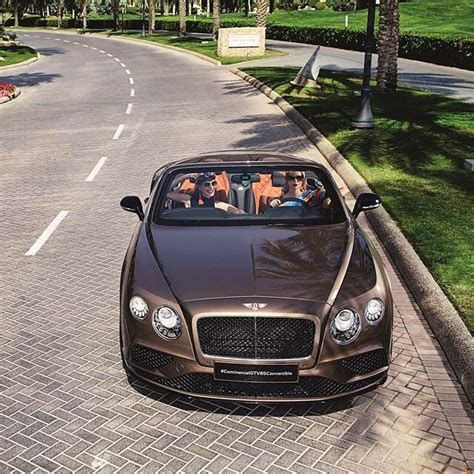 A Brown Car Driving Down The Road With People In It