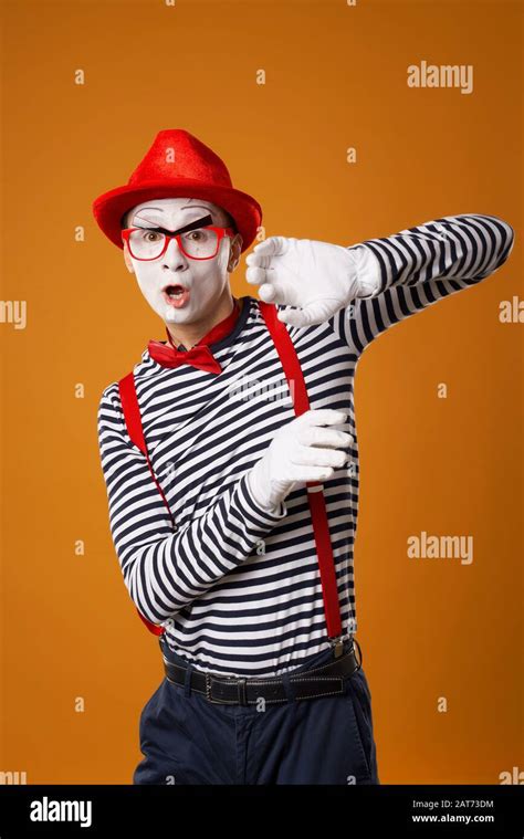 Serious Young Mime In White Gloves And Red Hat Looking At Camera On