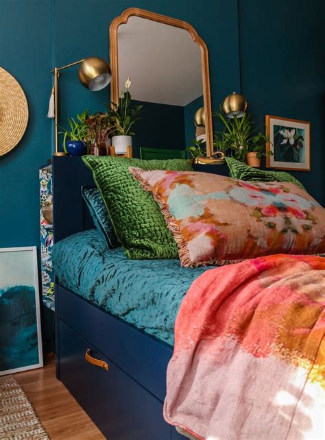 A Bedroom With Blue Walls And Colorful Bedding Plants On The Headboard