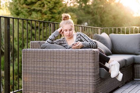 Teenage Girl Sitting Outside Using Her Phone At Sunset By Stocksy Contributor Angela Lumsden