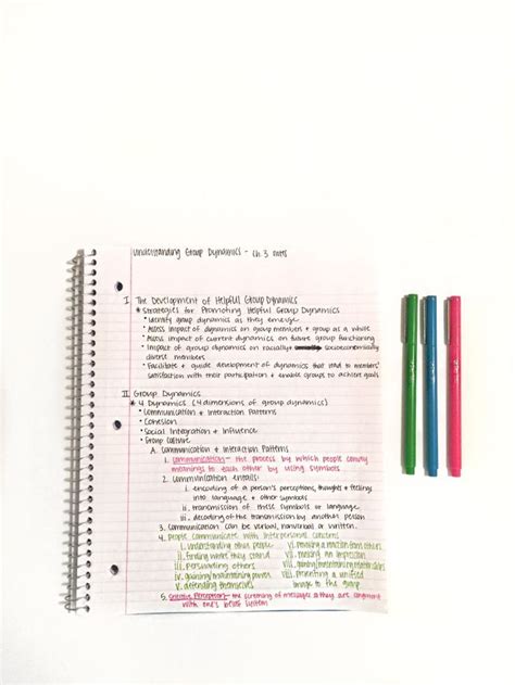 An Open Notebook With Colored Pencils Next To It On Top Of A White Surface