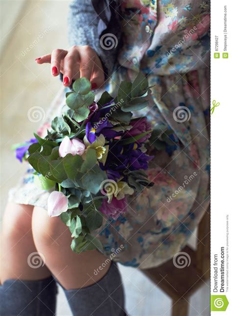 Girl Sitting On A Chair And Holding A Bouquet Of Flowers In Her Stock