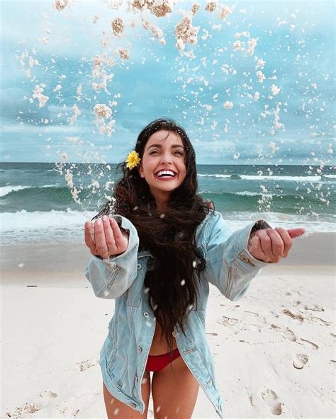 A Woman On The Beach Throwing Sand In The Air With Her Arms Wide Open And Smiling