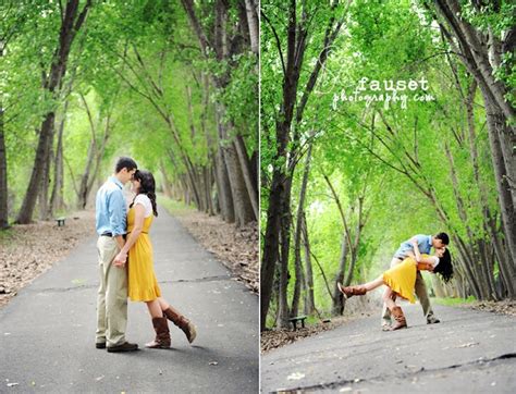 An Engaged Couple Kissing In The Middle Of A Tree Lined Road With Trees