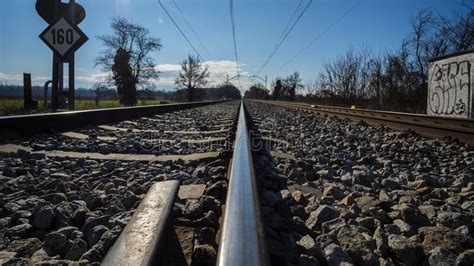 Straight Railway Track Perspective Over Stones On A Solid Blue Sunny