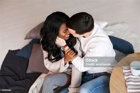 젊은 인종 간 부부는 바닥에 앉아 껴안고 키스 흑인 소녀는 백인 남자의 손을 잡고 있다 한 남자가 아프리카계 미국인을 부드럽게 껴안는다 2명에 대한 스톡 사진 및 기타