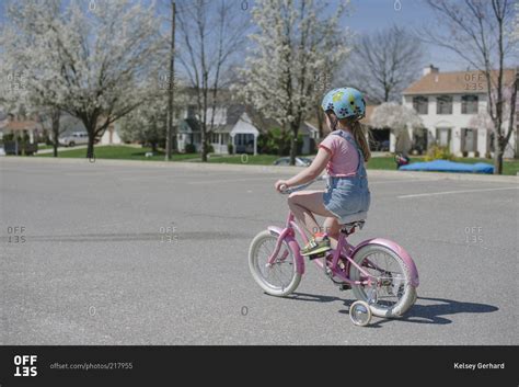 Little Girl Riding A Pink Bike With Training Wheels Stock Photo Offset
