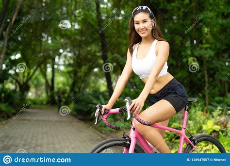 Giovane Bella Ragazza Sorridente Di Sport Che Guida Bicicletta Rosa Nel Parco Immagine Stock