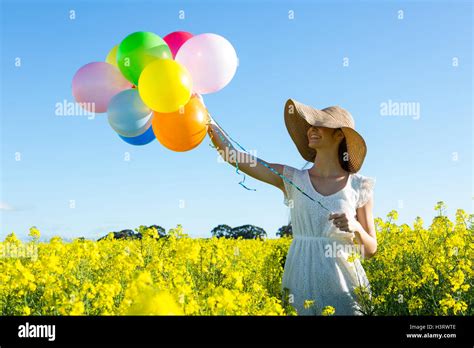 Woman Holding Colorful Balloons In Mustard Field Stock Photo Alamy