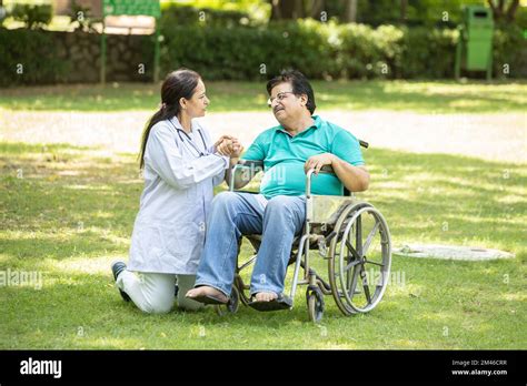 Indian Caregiver Nurse Taking Care Of Senior Male Patient In A