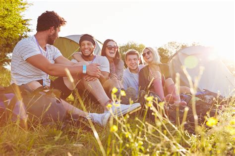 Group Of Friends Relaxing Outside Tents On Camping Holiday