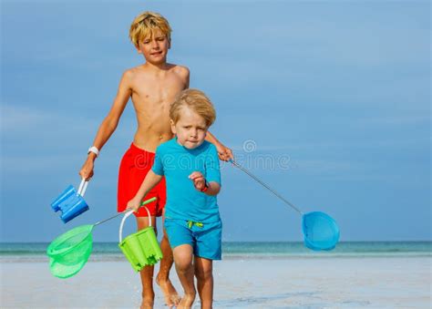 Close Portrait Of Two Boys On A Beach With Buckets And Hoop Net Stock