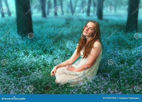 Portrait Of Beautiful Redhead Girl Sitting On The Meadow With Forget Me Not Flowers Stock Image