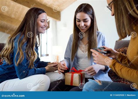 Two Beautiful Young Women Exchanging A T While Their Friend Takes A