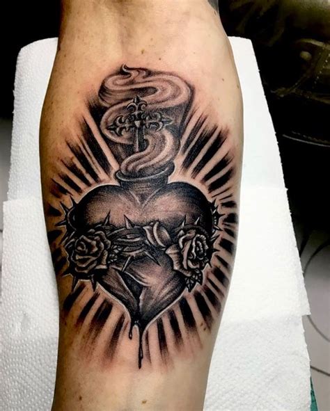 A Black And White Tattoo On The Leg Of A Person With A Cross Heart And
