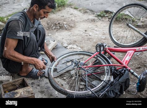 A Bicycle Repair Man Fixing A Flat Tire On A Bike On A Late Afternoon