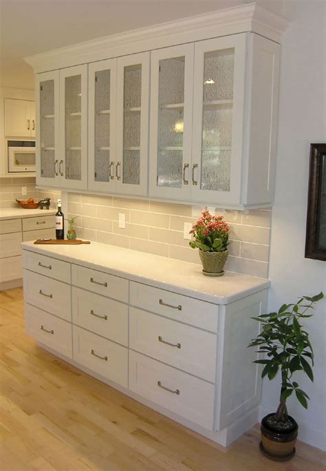 There is a wall that currently has no cabinets that we envision putting a 12 deep floor to ceiling pantry cabinet on the end. woman standing in tall aisle kitchen with white brick wall ...