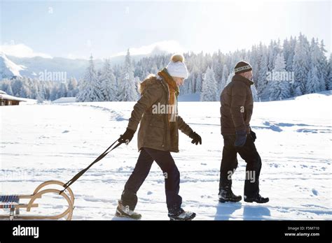 Side View Of Senior Couple On Snowy Landscape Pulling Sledge
