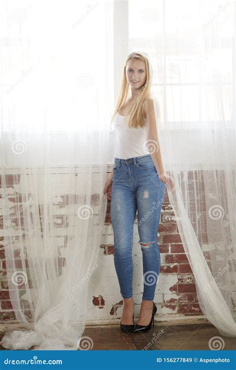 Beautiful Blonde Teen Poses In Studio Wearing White Tank And Jeans