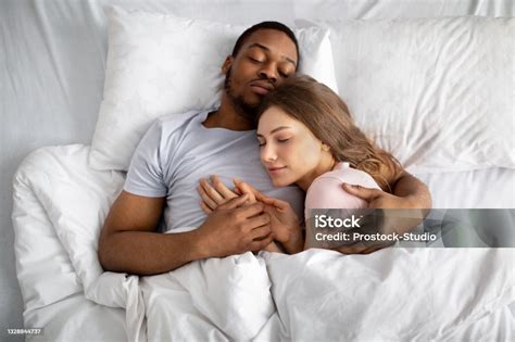 Top View Of Loving Interracial Couple Sleeping In Bed Embracing Each
