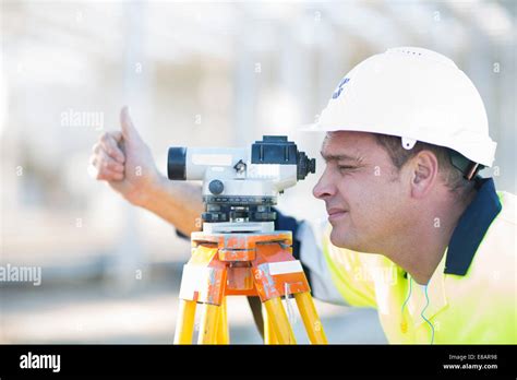 Surveyor looking through level on construction site Stock Photo - Alamy