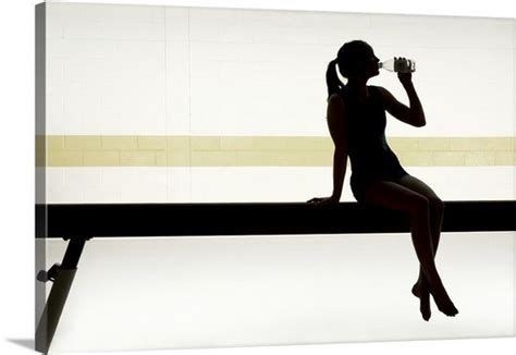 Female Gymnast Sitting On Balance Beam Drinking Water