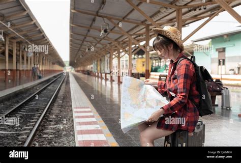 Young Woman Traveler With Backpack Looking To Map While Waiting For Train Asian Backpacker On