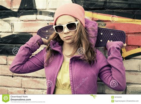 Teenage Girl Holds Skateboard Brick Wall With Graffiti