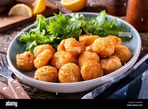 A Plate Of Delcious Breaded And Deep Fried Scallop Bites With A Side