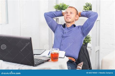 Young Businessman Sitting Relaxed With Hands Behind His Head Dreaming