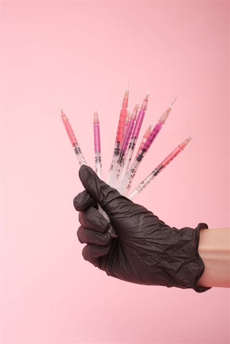 Faceless doctor showing colorful syringes in pink studio · Free Stock Photo