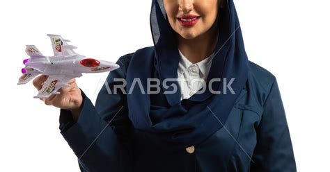 بورتريه لمضيفة طيران عربية خليجية سعودية مبتسمة ترتدي زي مضيفات الطيران تحمل مجسم مصغر لطائرة