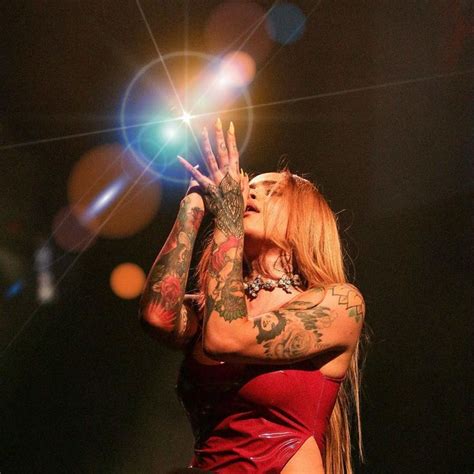 A Woman With Tattoos On Her Arms And Hands In Front Of The Light From Behind