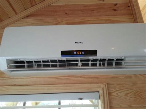 A White Air Conditioner Sitting On Top Of A Wooden Wall Next To A Window
