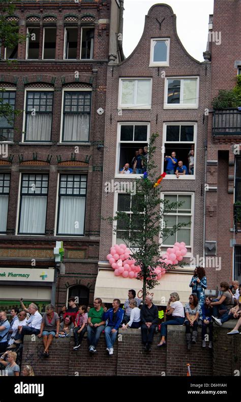 the gay pride parade down a crowded canal lined with people and boats in amsterdam holland