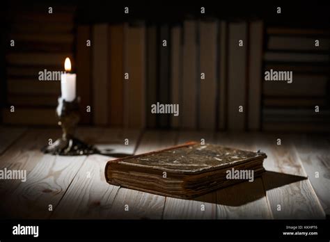Candle Light With Old Book On Wooden Table In The Night Dark Room With