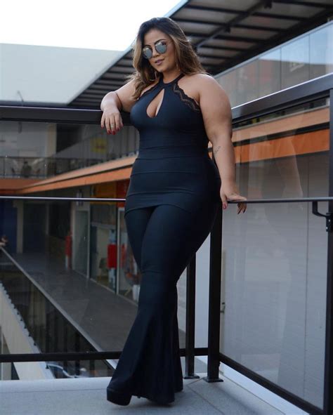 A Woman In A Black Dress Posing On A Balcony