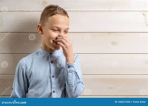 A 10 Year Old Boy In A Blue Shirt Smiles On A Light Wooden Background