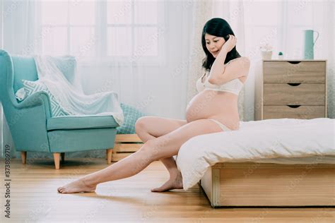 Slim Beautiful Asian Korean Pregnant Woman Sitting On Bed In Bedroom At Home With Lake Blue