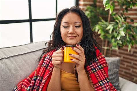 Young Chinese Woman Drinking Coffee Sitting On Sofa At Home Stock Image