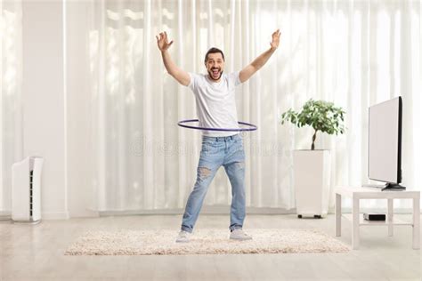 Cheerful Man Spinning A Hula Hoop And Smiling At Home Stock Photo
