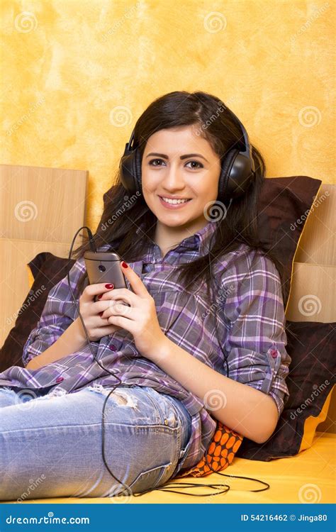 Portrait Of Beautiful Happy Girl Lying On A Bed With Headphones Stock
