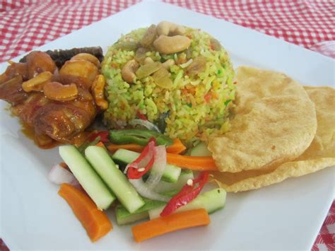 Nasi kaya rempah ini biasa disajikan dengan daging kambing atau ayam. Nasi Hujan Panas bersama Ayam Masak Merah Cendawan Butang