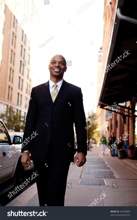 A Street Portrait Of A Business Man Walking Down The Sidewalk Stock