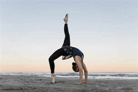 Flexible Ballet Dancer Bending Over Backwards While Practicing At Beach