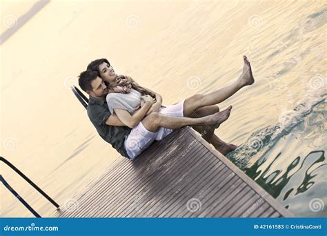 Couple Having Fun Seated On A Boardwak With A Beautifull Lake View