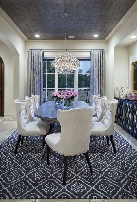 For longer, more rectangular tables, choose an oval rug that has enough room for the table and chairs to sit comfortably. cream-colored dining room with grey rug, curtains and ...
